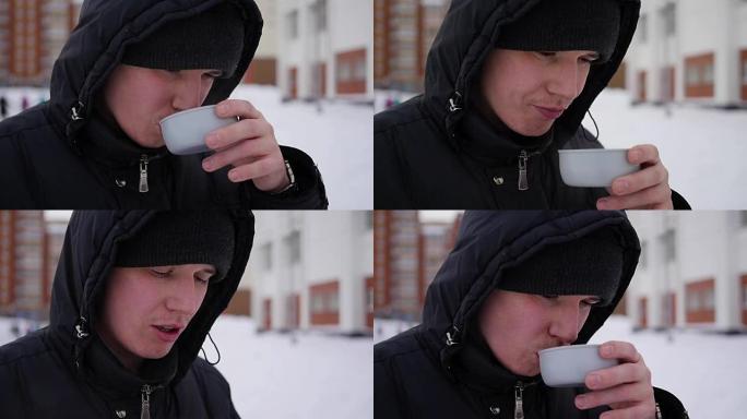 这家伙在冬天的户外喝杯子里的热茶。特写