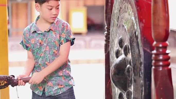 亚洲小男孩在一个大的古董泰国锣 (钟) 上刘海