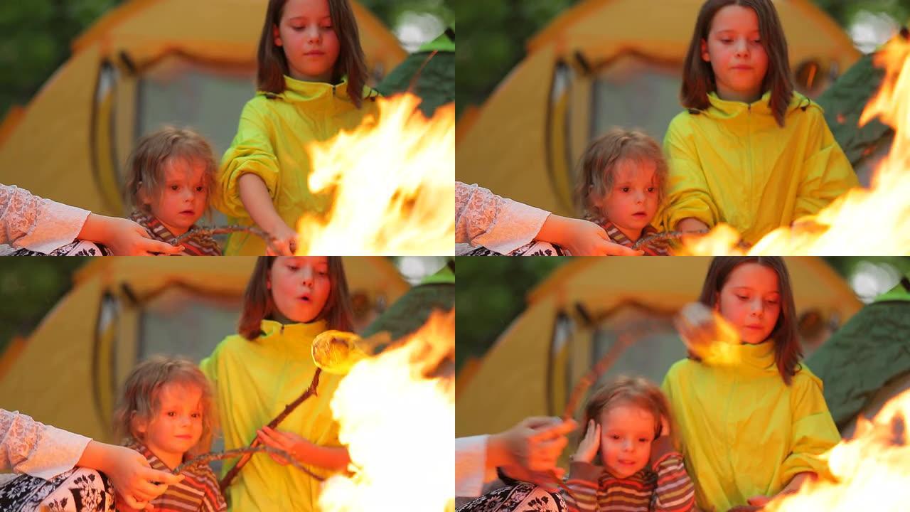 男孩和女孩在篝火上烤棉花糖