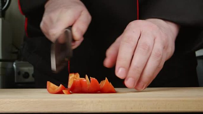 厨师在厨房的砧板上切甜椒