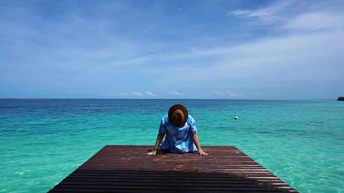 坐在木甲板上的人在宁静平静的大海和美丽的天空中放松