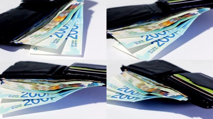 在开放式黑色皮革钱包中旋转各种以色列谢克尔钞票