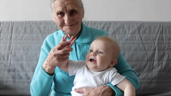 一位年迈的祖母怀里抱着一个小孙子，和他一起玩。