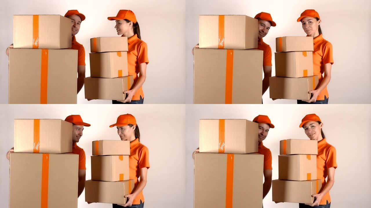 穿着橙色制服的男女快递员运送多个纸箱。浅灰色背景，全高清工作室拍摄