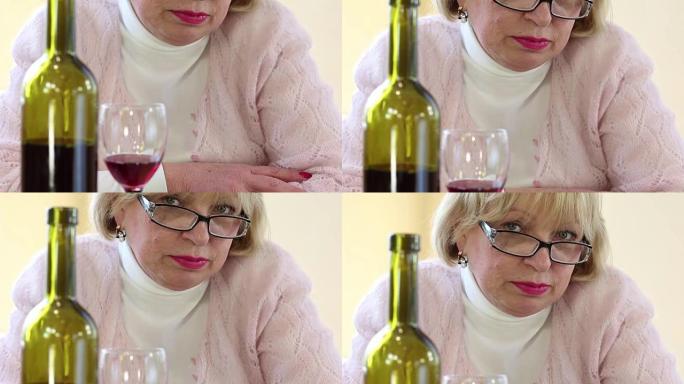 沮丧的高级妇女在桌子上拿着一瓶酒看着相机