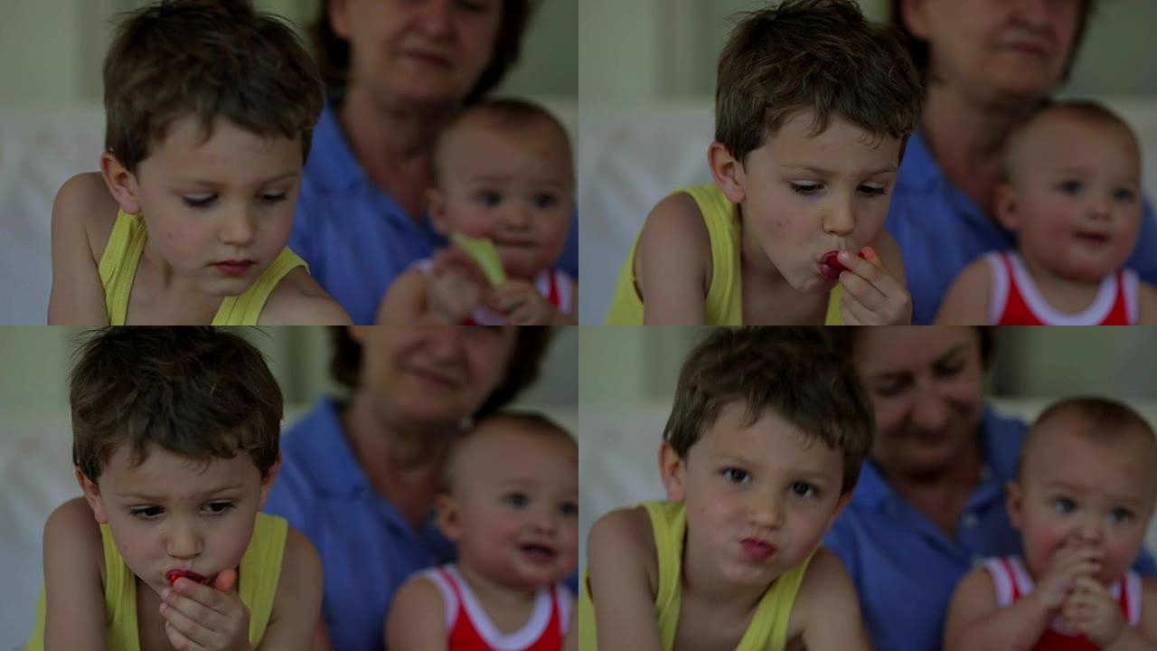 一个英俊的小男孩在背景中与他的祖母和婴儿兄弟一起吃水果的随意肖像