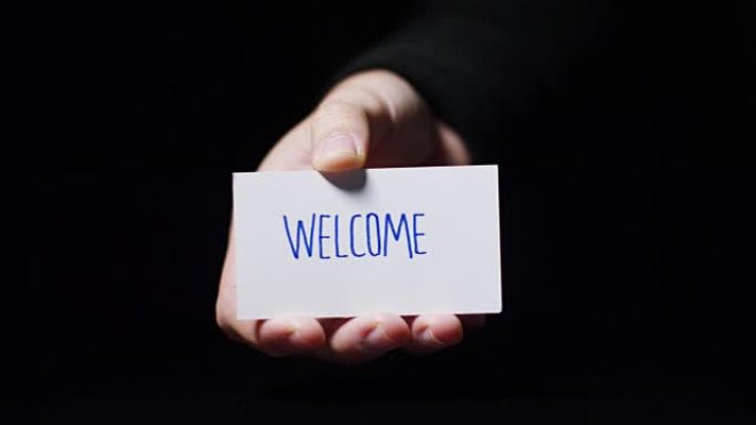 一只手展示一张写着 “欢迎” 的卡片。概念: 欢迎、好客、客户服务、服务台