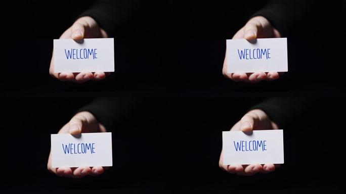 一只手展示一张写着 “欢迎” 的卡片。概念: 欢迎、好客、客户服务、服务台