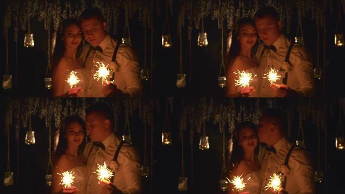 幸福的已婚夫妇在户外燃烧孟加拉灯。在晚上的婚礼上，散焦的新郎和新娘彼此相爱。