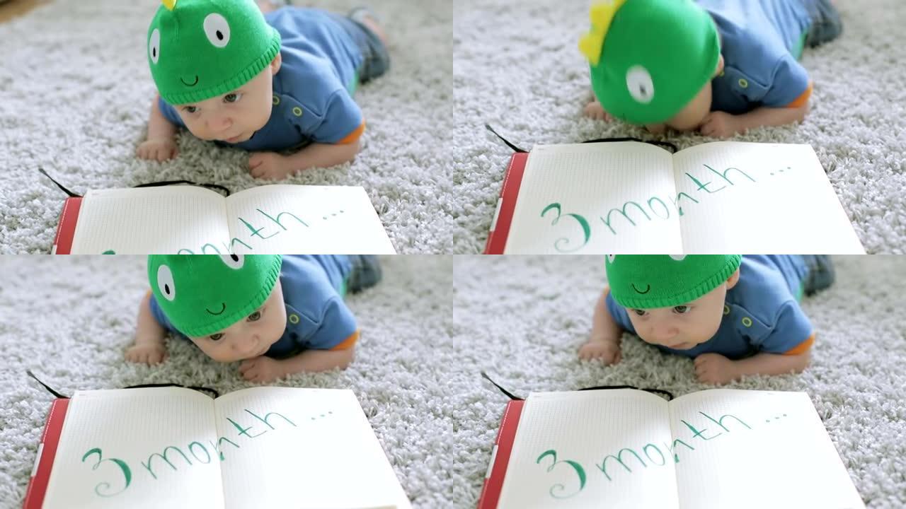 戴着绿龙帽子的三个月婴儿躺在地板上的笔记本上。
