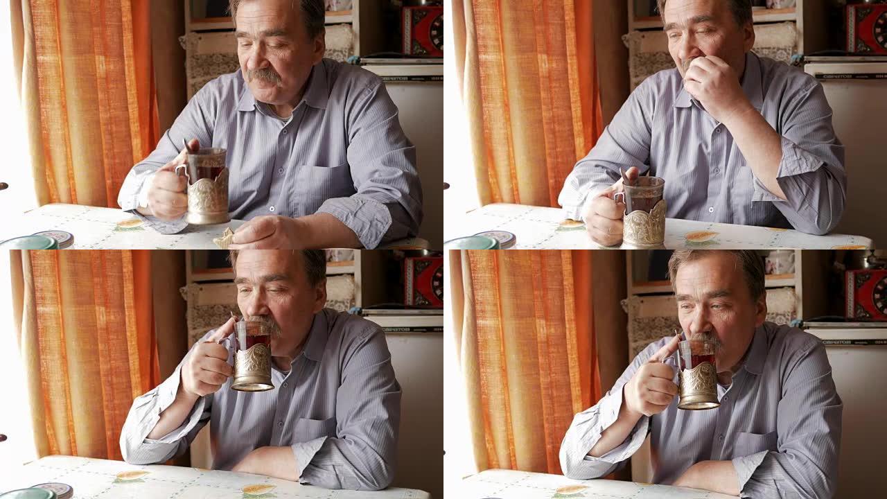 一位留着小胡子的老人拿着一杯热饮和饮料。他坐在窗户附近，在家吃早餐