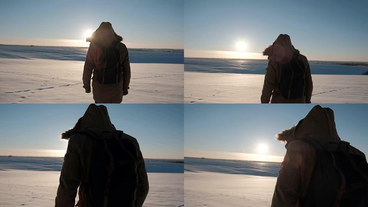 一个穿着背包的夹克的男人在冬天的日落中上场