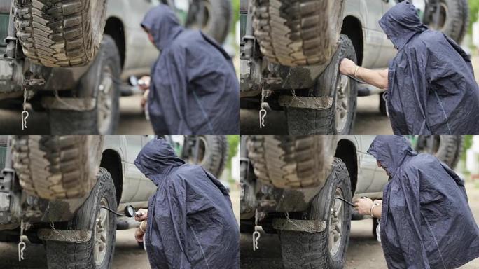 穿着雨衣的男子在路边抽越野车的车轮