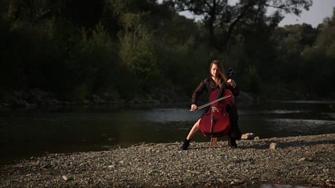 可爱的女孩正在河边演奏大提琴