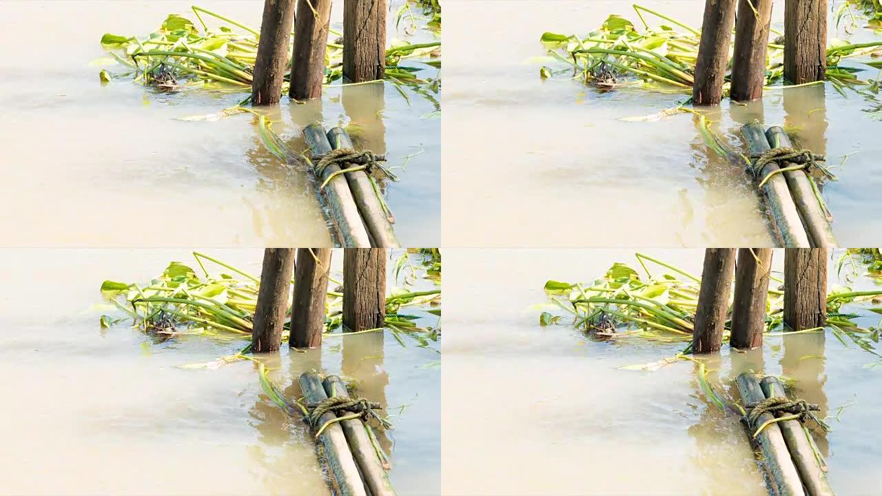 竹木树干绑在一起漂浮在水面上，作为屏障，防止垃圾和水葫芦进入河岸。干净的棕色水编织，可以看到周围的小