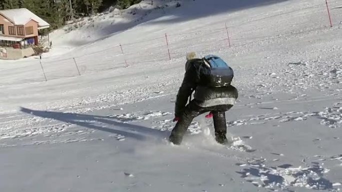小女孩从冬天的雪地滑雪坡上跑下来，慢动作