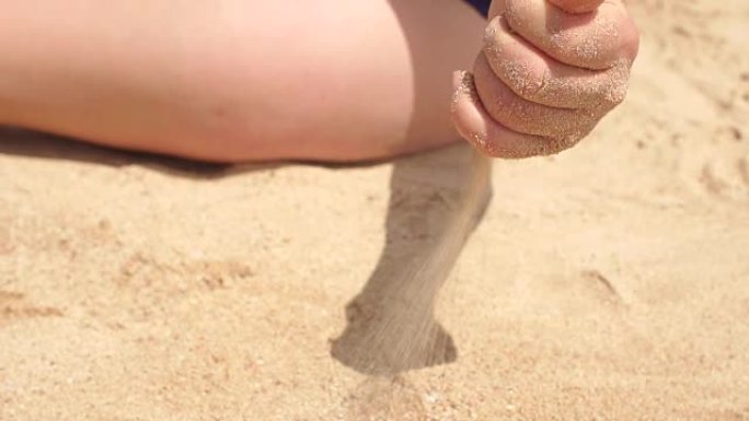 女孩正在沙滩上浇沙子，慢动作。