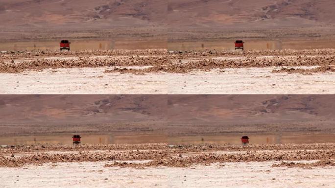 红色汽车在阿塔卡马沙漠的公路旁开走。