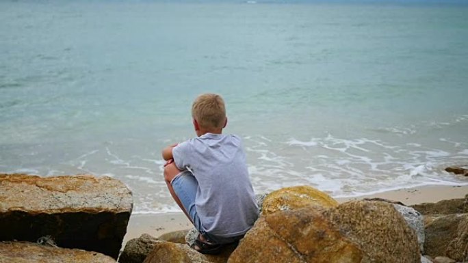泰国。孩子坐在海边，向远处望去