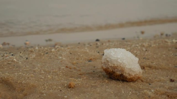 关闭以色列死海沙滩上的盐沉积物。背景上的水。