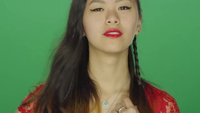 年轻的亚洲女子在绿屏工作室背景上凝视和调情