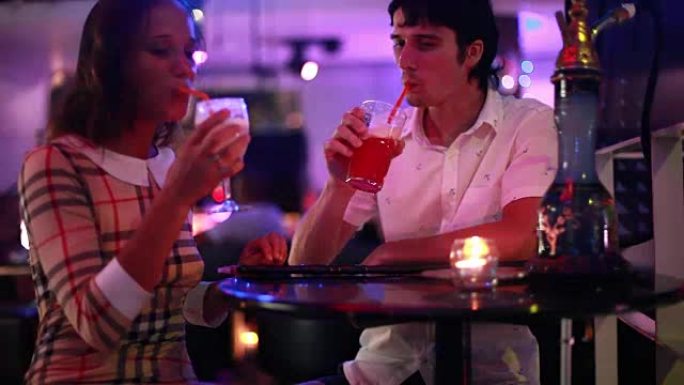 年轻漂亮的夫妇约会时调情，在派对期间在夜总会酒吧喝鸡尾酒抽水烟。1920x1080