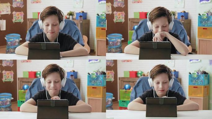 可爱的小男孩使用数字平板电脑观看有趣的视频，戴着耳机