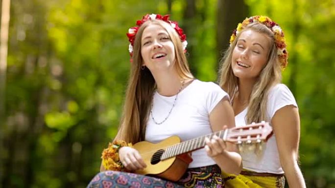 两个年轻女孩在夏天的森林里拿着吉他