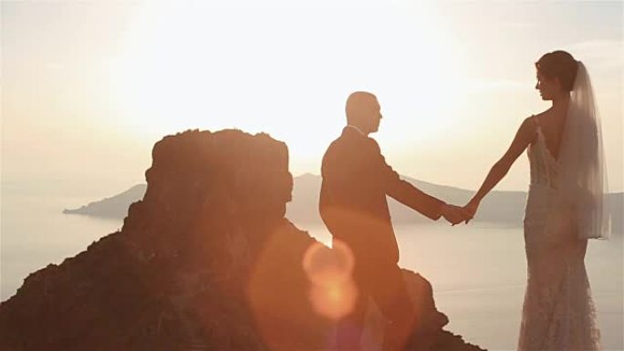 浪漫的神话般的情侣温柔地牵着手看着日落天空背景下山顶的景色