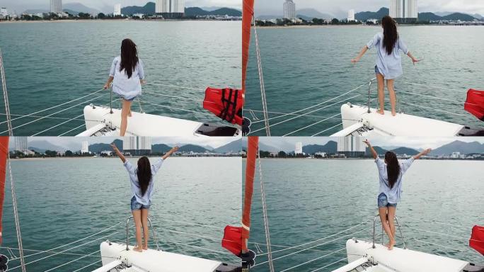 年轻女子在游艇上航行时看着大海，举手