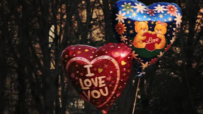 带有标题 “我爱你” 和泰迪熊图片的心形气球在风中摇曳
