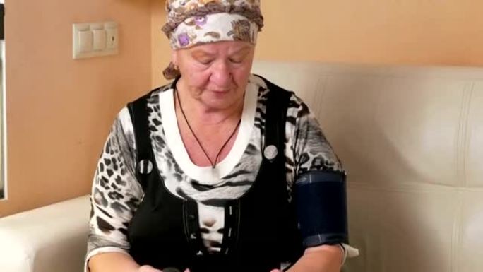 年龄较大的妇女在家中测量血压。她戴着袖口，医疗设备的证词看起来很仔细