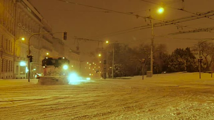 扫雪机和警车骑在冰雪覆盖的广场上，中欧，夜晚
