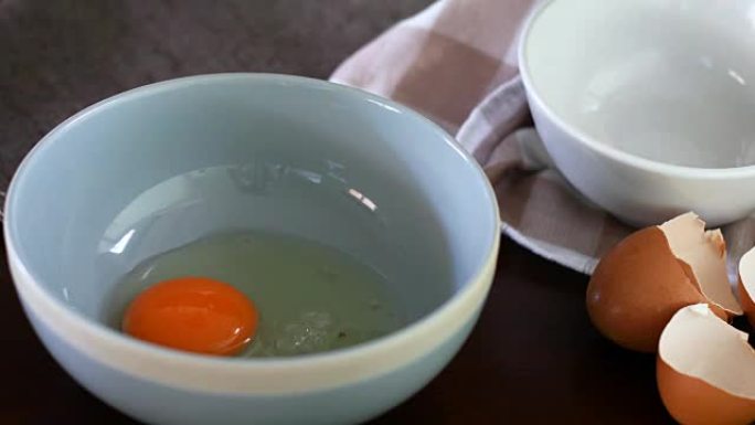 关闭厨师手将鸡蛋制动到蓝色碗中，然后混合以准备煎蛋卷烹饪，4k Dci分辨率
