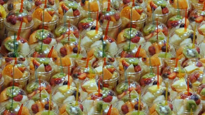 水果市场货架上的塑料玻璃杯中混合不同的水果