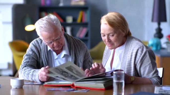 老年幸福夫妇看着旧相册，微笑着