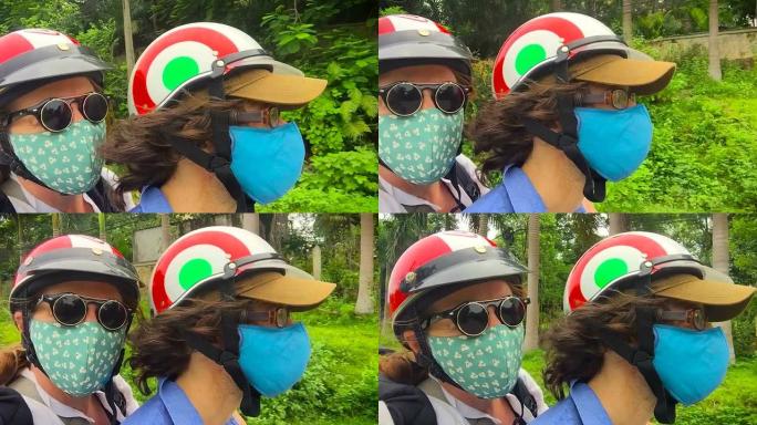 在热带地区，两个人骑着戴着口罩和头盔的踏板车的特写镜头