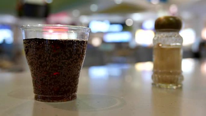 一杯可口可乐和胡椒在购物中心内的桌子上