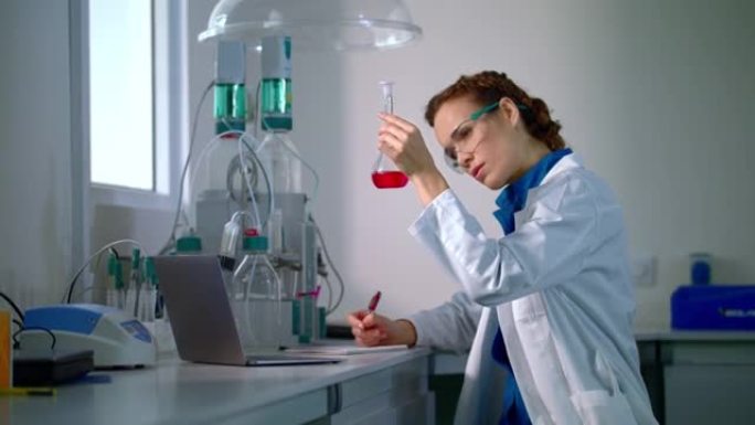 科学家找到了治疗方法。女科学家在实验室烧瓶中观察化学液体