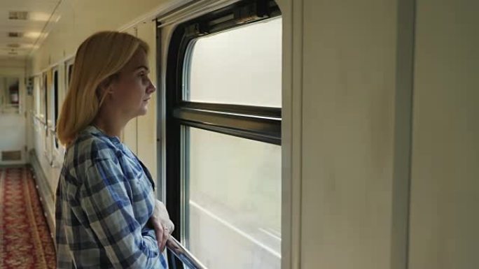 一名年轻女子向火车窗外望去。它在走廊里，火车开得很快。梦想和旅行