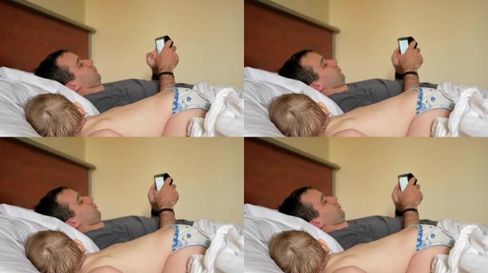 父亲在熟睡的婴儿附近的平板电脑上阅读新闻。一个男孩在床上的房子的前景中休息