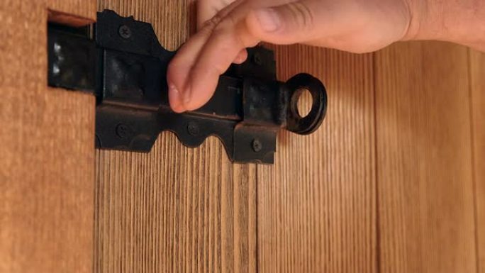 用黑色滑动螺栓解锁木板门上的挂锁