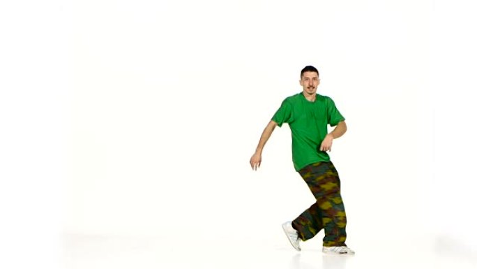 穿着绿色衬衫的年轻舞者继续在白色上跳霹雳舞