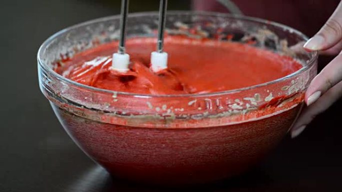 用电动搅拌机敲打面团特写。制作红色天鹅绒蛋糕