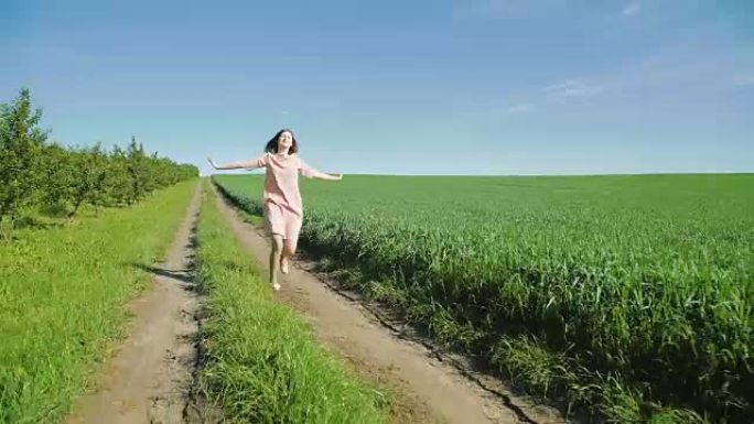 美丽的姑娘奔跑在麦田间的小路上，背景很美