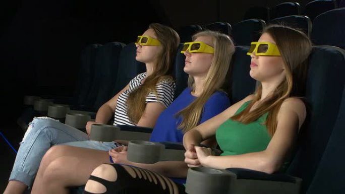 在电影院看电影的年轻朋友，3d眼镜