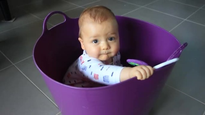 婴儿在紫色洗衣篮中玩耍