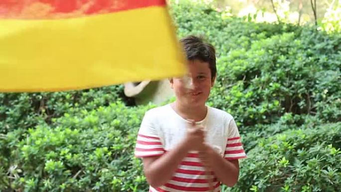 小男孩在外面微笑着，挥舞着德国国旗