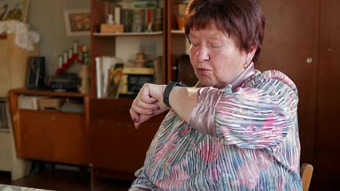 一位老妇在智能手表上检查信息。她阅读提醒并说出搜索短语。阅读结果后