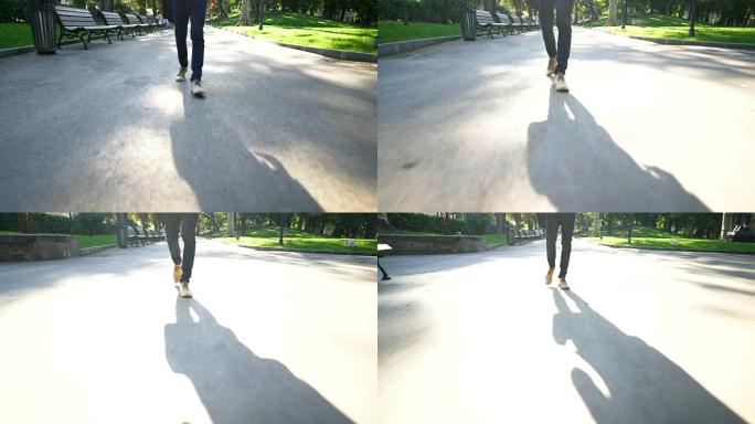 移动摄像机拍摄的脚和早晨一个人在公园小巷上行走的阴影